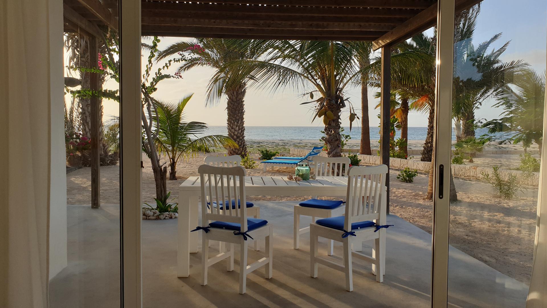 Terrasse des Strandhauses Boa Vista mit Blick auf Palmen und das Meer bei Sonnenuntergang